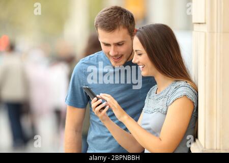 Happy and Paar prüfen Inhalt in einem smart phone stehen auf der Straße Stockfoto