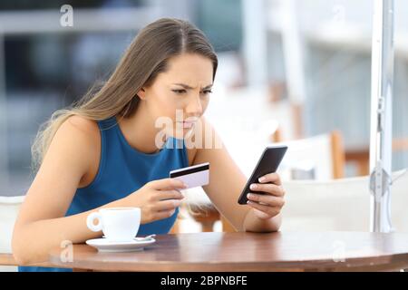 Single besorgt Mädchen Probleme mit der Bezahlung Online mit Kreditkarte und einer Telefonnummer in einem Café Terrasse Stockfoto