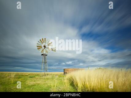 Langbelichtungs-Bild mit Windmühle und Damm und streifigen Wolken über dem Kopf Stockfoto