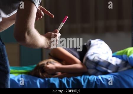 Vater bittet um Erläuterung, Schwangerschaft Test zu einem traurigen schwangere Teenager, der beklagt liegen auf dem Bett in Ihrem Zimmer Stockfoto