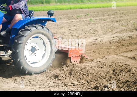 Traktor mit Fräsmaschine löst, mahlt und mischt Erde. Landwirtschaft und Landwirtschaft. Lockern der Oberfläche, Anbau des Landes für die weitere Pflanzung Stockfoto