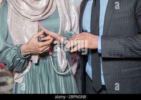Hochzeitshände einer Braut und Bräutigam . Bräutigam legte einen Ring auf den Finger seiner schönen Frau. Junger Mann, der nach der Heirat einen Ring auf den Finger seiner Verlobten legt Stockfoto