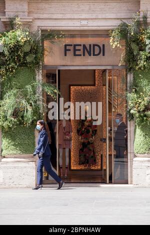 Ein Fußgänger, der eine schützende Gesichtsmaske trägt, geht am Dienstag, den 19. Mai 2020 am Fendi-Laden in der Innenstadt von Rom, Italien, vorbei. Geschäfte Und Restaurants Werden Wieder Eröffnet, Da Italien Die Lockdown In Phase 2 Weiter Lockert Stockfoto