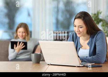 Zwei entspannte Mitbewohner mit mehreren Geräten mit Wi-fi Verbindung zu Hause Stockfoto