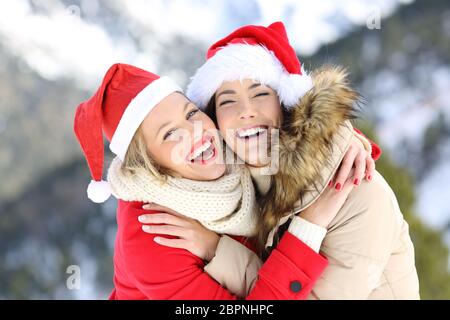 Zwei glückliche Freunde in den weihnachtsferien schauen Sie mit einem schneebedeckten Berg im Hintergrund Stockfoto