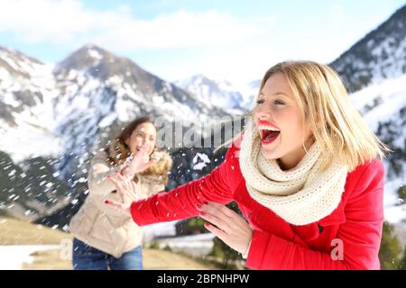 Zwei lustige Freunde scherzen das Werfen mit Schneebällen im Berg auf Winterurlaub Stockfoto