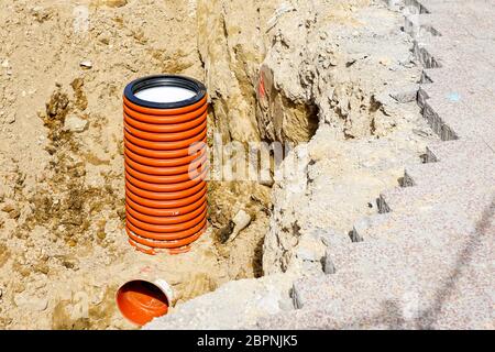 Austausch von Kommunikation auf der Stadtstraße, vertikales Ende der orangefarbenen Kunststoffrohr in Sandgraben Stockfoto