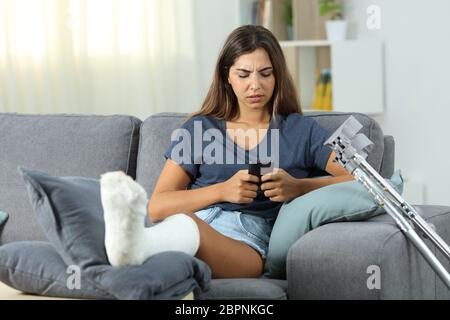 Vorderansicht eines behinderten Mädchen Messaging mit einem Smart Phone auf der Couch zu Hause sitzen Stockfoto