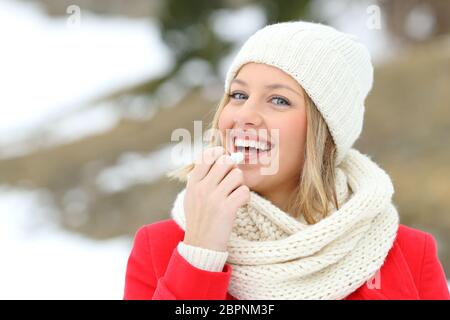 Glückliche Frau Anwendung Lippenbalsam im Freien im Winter in der verschneiten Berg Stockfoto