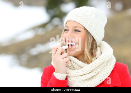 Mädchen schützende Lippen mit Lippenbalsam im Winter mit einem schneebedeckten Berg im Hintergrund Stockfoto