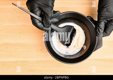 Werkzeuge zum Färben in Friseurhand auf dem Holzhintergrund. Färbung der Haare zu Hause Stockfoto