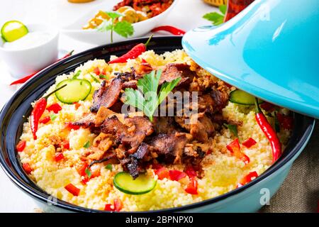 Tajin mit Couscous, Gemüse und Fleisch auf weißem Hintergrund Stockfoto
