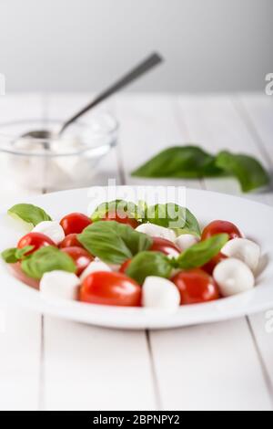 Frischen mozzarella Kugeln mit Cherry Tomaten und grüne Basilikum auf weißem Hintergrund. Italienisches Essen Konzept. Soft Focus. Stockfoto