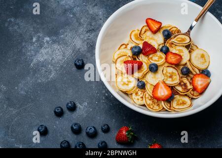 Zum Frühstück gab es winzige Pfannkuchen. Pfannkuchen mit Erdbeeren und Heidelbeeren am Morgen zum Frühstück in der Küche zu Hause gekocht. Hintergrund Der Lebensmittel. Stockfoto