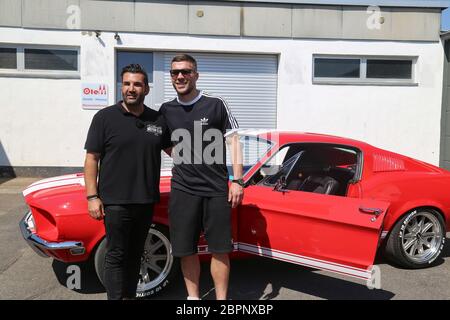 Lukas Podolski - Mustang - der deutsche Fußballspieler Lukas Podolski kommt sein neues Auto und Orkan Sahin - Oldtimer-Experte (links) Stockfoto