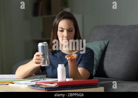 Verdächtige student Vergleich vitamin Pille ergänzen und energy drink versucht, zu Hause in der Nacht zu entscheiden, Stockfoto