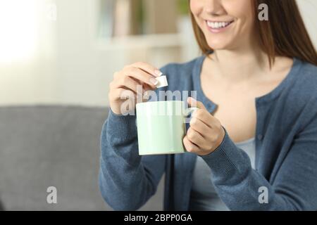 Nahaufnahme von einem Smiley Frau Zucker in Kaffee Becher auf einer Couch im Wohnzimmer zu Hause sitzen Werfen Stockfoto