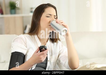 Frau mit einem niedrigen Blutdruck trinken süße Limo auf einer Couch im Wohnzimmer zu Hause sitzen Stockfoto