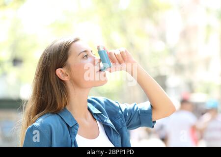 Seitenansicht portrait einer Asthmatischen Frau mit einem Inhalator draußen auf der Straße Stockfoto