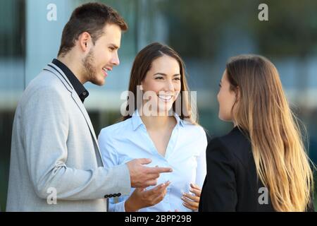 Drei glückliche Führungskräfte stehen auf der Straße mit einem Bürogebäude im Hintergrund Stockfoto