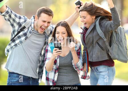 Drei aufgeregt Studenten Prüfung Prüfung Noten online in einem smart phone Stockfoto