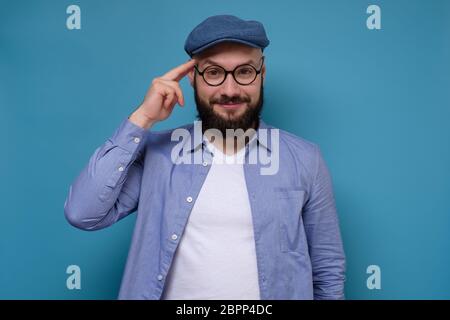 Reifer europäischer Mann mit Bart hält Finger auf Schläfen, er hat eine tolle Idee und hatte den besten Plan, was jetzt zu tun. Studioaufnahme Stockfoto