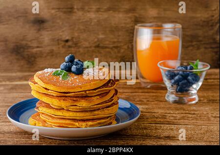 Stapel Kürbispfannkuchen mit Heidelbeeren auf rustikalem Holzhintergrund. Kopierbereich. Stockfoto