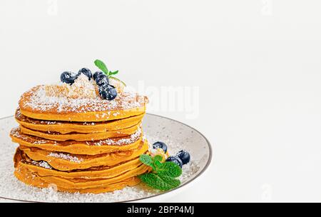 Stapel Kürbispfannkuchen mit Heidelbeeren und Minze auf weißem Hintergrund. Kopierbereich Stockfoto