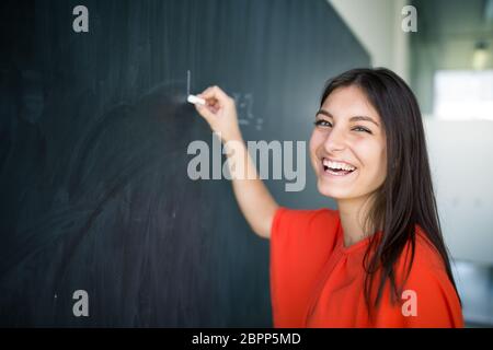 Hübsche, junge College-Student schreibt an die Tafel/Tafel während einer Math-Klasse Stockfoto