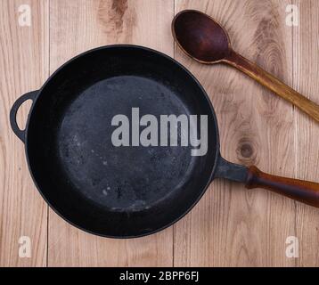 Leere schwarze runde Pfanne mit Holz- auf einen hölzernen Tisch Griff, Ansicht von oben Stockfoto