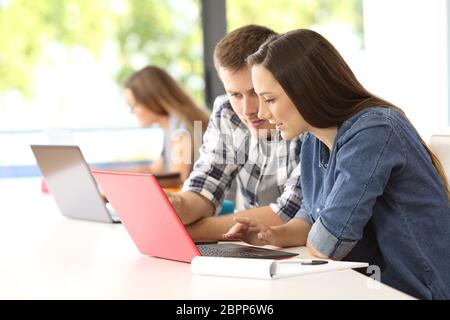 Zwei konzentrierte Studenten arbeiten zusammen auf der Linie mit einem Laptop in einem Klassenzimmer Stockfoto