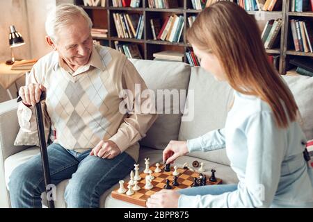 Vater und Tochter zu Hause Bibliothek sitzen Schach spielen glücklich Stockfoto