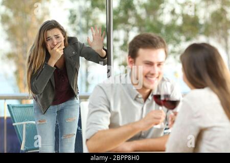 Cheater von seiner traurigen Freundin aus mit einem anderen Mädchen in einem Café gefangen Stockfoto