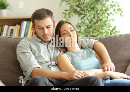 Gelangweilte Paar verschwendete Zeit auf einem Sofa zu Hause sitzen Stockfoto