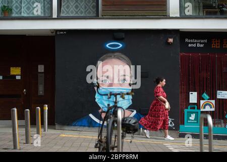MANCHESTER, Großbritannien EINE Frau geht vor einem Wandbild einer Krankenschwester mit einer PPE-Gesichtsmaske, das der Künstler Akse im Northern Quarter von Manchester gemalt hat. Dienstag, 19. Mai 2020. (Quelle: Pat Scaasi) Quelle: MI News & Sport /Alamy Live News Stockfoto