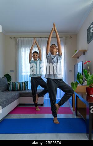 Kinder machen Sportübungen, üben Yoga zu Hause. Sport, gesunder Lebensstil, aktive Freizeit zu Hause Stockfoto