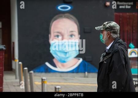 MANCHESTER, Großbritannien EIN Mann in einer Gesichtsmaske geht vor einem Wandbild einer Krankenschwester mit einer PSA-Gesichtsmaske, das vom Künstler Akse im Northern Quarter von Manchester gemalt wurde. Dienstag, 19. Mai 2020. (Quelle: Pat Scaasi) Quelle: MI News & Sport /Alamy Live News Stockfoto