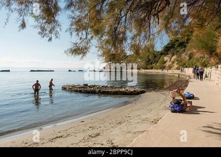 Einheimische und Touristen genießen einen sonnigen Sommertag am Strand Bacvice, Split, Kroatien Stockfoto