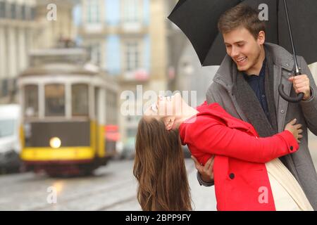 Spielerische Brautpaar in Liebe dating scherzen und Lachen auf der Straße der Altstadt an einem regnerischen Tag unter einem Regenschirm Stockfoto