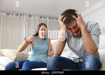 Paar streiten. Frau schreien zu ihrem verzweifelten Mann sitzt auf einer Couch im Wohnzimmer zu Hause Stockfoto