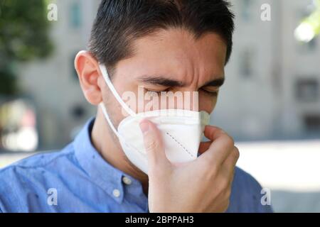 COVID-19 Close Up Sick man mit KN95 FFP2 Maske Niesen oder Husten. Porträt des Mannes mit Gesichtsmaske gegen SARS-CoV-2 niesen im Freien. Stockfoto