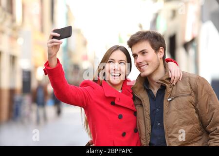 Glückliches Paar selfies mit einem Smart Phone auf der Straße im Winter Stockfoto