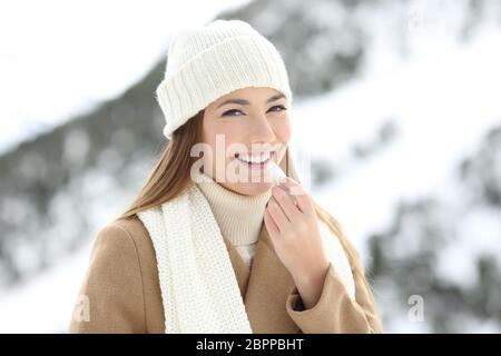 Glückliche Frau Anwendung Lippenbalsam im Winter Urlaub in die schneebedeckten Berge Stockfoto