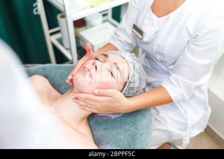 Arzt Kosmetikerin macht kosmetische Gesichtsmassage. Frau entspannt sich auf einem Kosmetikstuhl Stockfoto