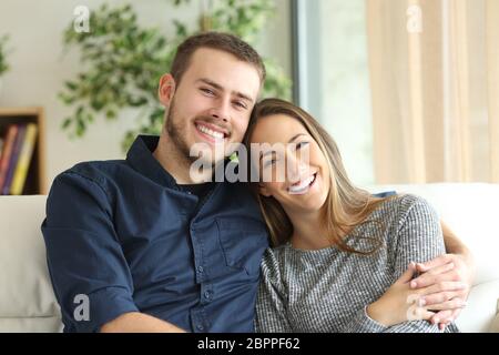 Vorderansicht Porträt eines glücklichen Paares posieren und Blick in die Kamera sitzt auf einer Couch im Wohnzimmer zu Hause Stockfoto