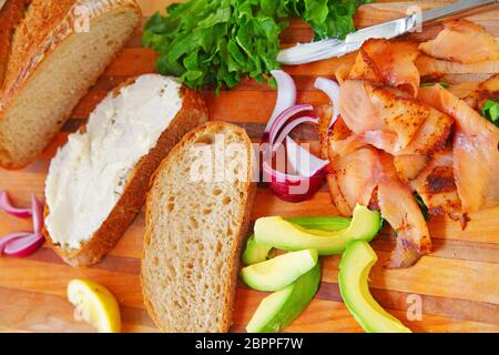 Blick über die Hängebäck, geräucherte Lachsscheiben, Avocado, rote Zwiebel, Salat und Frischkäse Stockfoto