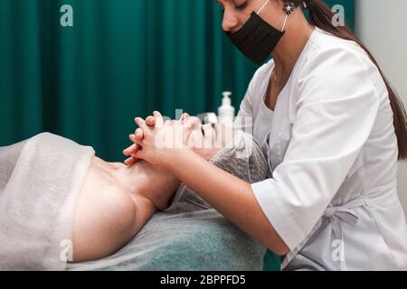 Arzt Kosmetikerin macht kosmetische Gesichtsmassage. Frau entspannt sich auf einem Kosmetikstuhl Stockfoto