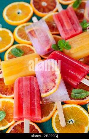 Gefrorene Eis am Stiel mit frischen Zitrusfrüchten und Minzeblättchen Stockfoto