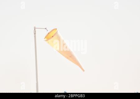 Orange Windsocke gegen blauen Himmel.Windsocke der Ausrüstung überprüfen die Windblasrichtung in der Tageszeit und kein Windwehen auf bewölkten Himmel bewölkt. Stockfoto