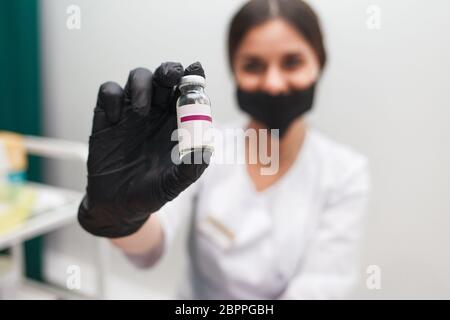 Die Kosmetologin hält eine Ampulle mit kosmetischer Substanz in den Händen. Arzt zeigt Botox-Ampulle. Stockfoto